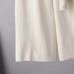 Primo piano dettagliato della texture del tessuto in maglia beige, lavorazione fine.