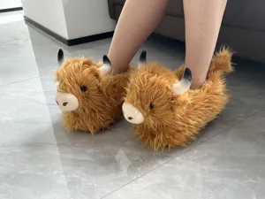 Vista dettagliata delle pantofole di peluche con mucche delle Highland, scarpe calde.