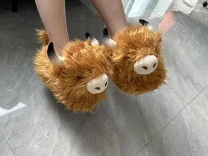 Vista dettagliata di pantofole peluche mucca delle highland, calde scarpe da casa invernali.