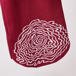 Détail de vêtement en tricot rouge avec motif tissé blanc abstrait, gros plan de vêtement décontracté.