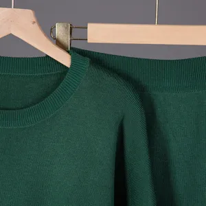 Dark green knit sweater detail showing soft texture, crew neck design, and cozy autumn style.