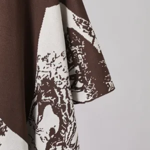 Close-up detail of brown and white jacquard knitwear shawl, showing clear texture and quality.