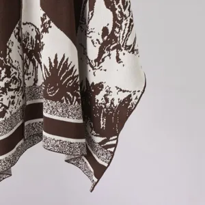 Brown and white knitted jacquard cape detail close-up showing luxurious vintage pattern texture.