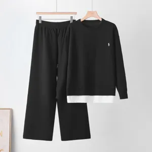 Detailed view of the black knit sweater and wide-leg pants set, featuring layered hem.