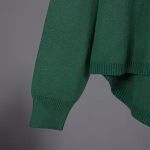 Close-up detail of dark green knitted sweater sleeve with ribbed cuffs and soft texture.
