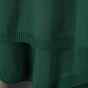 Close-up detail of dark green knit sweater showcasing soft texture and ribbed hem design.