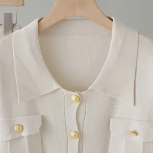 Beige knit polo top featuring a classic lapel collar, gold crest buttons, and chest pockets.