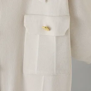 Close-up detail of knitted garment featuring a pocket and gold embossed button design.