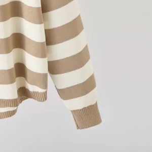 Close-up detail of women's beige and white striped knit sweater sleeve and ribbed cuff.