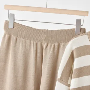 Knitted two-piece set detail close-up, striped sweater and solid pants, soft cozy texture.