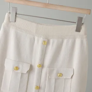 Elegant ribbed knit skirt detail with gold-tone embossed buttons and front pockets.