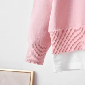 Pink knitted long sleeve top detail, crew neck design, elegant spliced hem style for women.