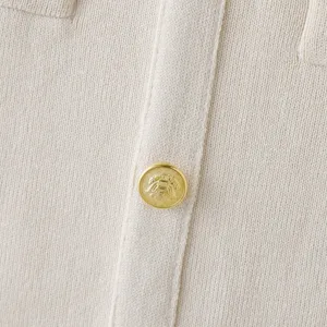 Beige knit cardigan close-up detail, featuring luxury gold embossed metal buttons.