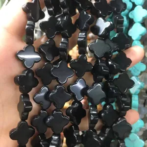 Close-up view of black stone clover-shaped loose beads for DIY jewelry necklace making.