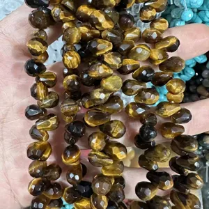 Gros plan de perles en pierre d'oeil de tigre à facettes en forme de larme pour bijoux DIY