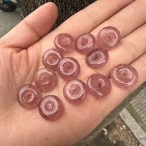 Detailed view of 15mm natural pink strawberry quartz donut beads held in a person's hand