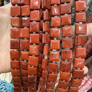 Close-up of natural red stone square beads with side grooves and curved surface for DIY jewelry