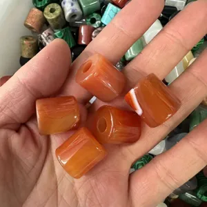 Macro view of 9x9mm orange carnelian cylinder beads held in hand for DIY jewelry