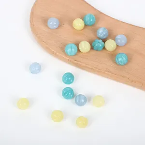 Macro view of colorful pastel natural stone pumpkin beads scattered on a wooden display board