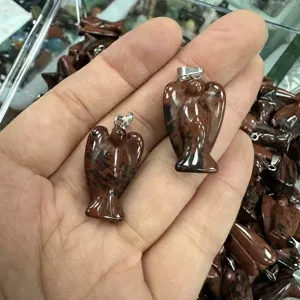 Detaillierte Makroansicht von zwei aus Naturstein geschnitzten Engelanhängern in der Hand