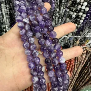 Macro detail of natural purple amethyst round beads with white chevron patterns.