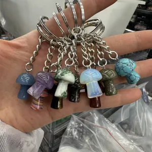 Hand-held display of various natural stone mushroom-shaped keychains and pendants.