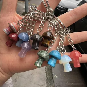 Hand holding various natural stone mushroom crystal keychains macro view