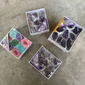 Detailansicht von natürlichen Amethyst-Clustern und Aura-Quarz-Geoden in Boxen