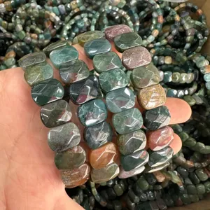 Close-up of faceted multi-color Indian agate slab bracelets held in hand
