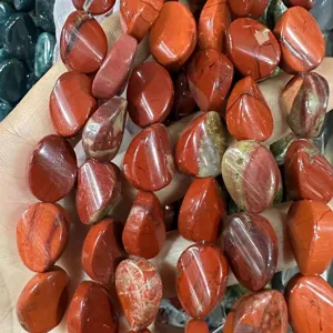 Primo piano di perle sciolte ovali in diaspro rosso naturale per gioielli fai da te