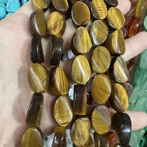 Primo piano di perle ovali in occhio di tigre naturale con chatoyancy dorato unico