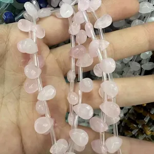 Primer plano de cuentas de corazón de cuarzo rosa natural con agujeros para bricolaje