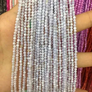 Close-up view of multiple strands of 2mm light blue round shell beads held in hand