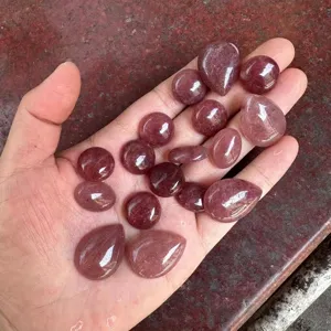 Macro view of natural strawberry quartz cabochons in various shapes held in hand