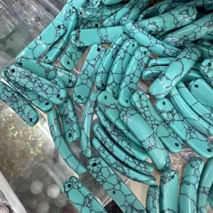 Nahaufnahme von türkisfarbenen Abstandsriegeln mit schwarzer Maserung für DIY-Schmuck