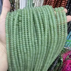 Macro detail of 4x6mm light green abacus-shaped natural stone beads for DIY jewelry making.
