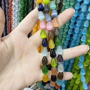 Detalle macro de cuentas de ojo de gato en forma de gota de colores para diseño de joyas DIY.