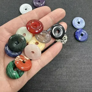 Close-up of assorted 20mm natural stone doughnut pendants held in hand