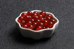 Close-up of natural red carnelian agate loose beads in a white flower ceramic dish
