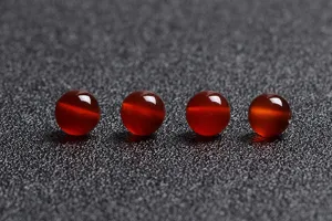 Close-up of four natural red agate round loose beads for DIY jewelry making.