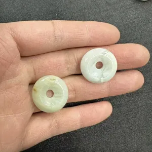 Close-up of 20mm natural light green stone donut beads held in hand for DIY jewelry