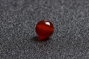 Close-up detail of a single polished translucent natural red agate bead for DIY jewelry
