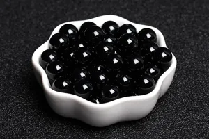 Close-up of natural black agate loose beads for DIY handmade jewelry crafting in a white bowl.