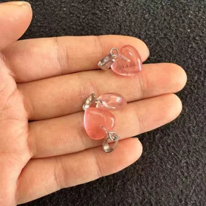 Nahaufnahme von 12 mm großen rosa Kristallanhängern in Herzform, zur Größenangabe in der Hand.