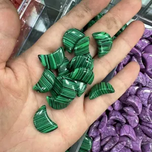 Gedetailleerde macro-opname van 20 mm groene maanvormige stenen met malachietpatroon in hand