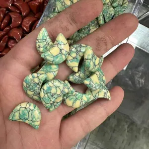 Gedetailleerde close-up van kleine groene maanvormige turkoois stenen vastgehouden in hand