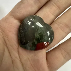 Nahaufnahme eines herzförmigen Blutstein-Ornaments, gehalten in der Hand, zeigt Textur.