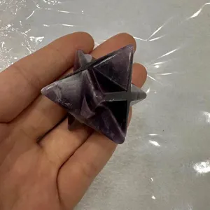 Nahaufnahme eines handgehaltenen lila Amethyst Merkaba Sternkristalls mit Natursteintexturen