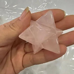 Hand hält einen durchscheinenden rosa Rosenquarz-Merkaba-Stern-Heilkristall