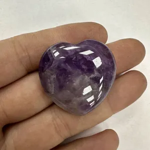 Nahaufnahme eines herzförmigen Amethyst-Kristalls in der Hand zur Detailansicht.